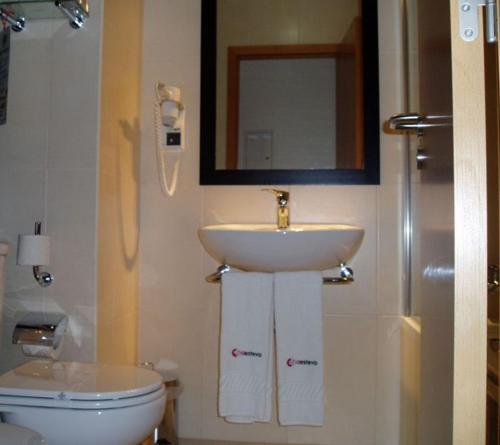 a bathroom with a sink and a toilet and a mirror at Hotel A Esteva in Castro Verde