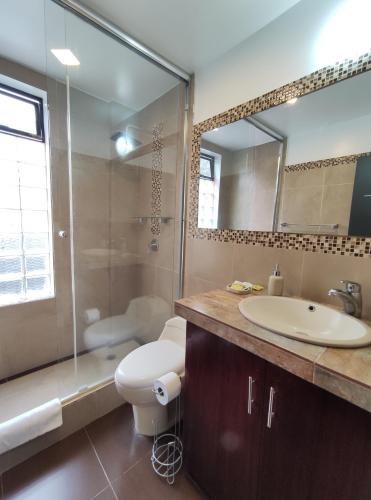 a bathroom with a toilet and a sink and a shower at Villa Cosmopolita in Baños