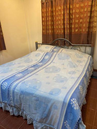 a bed with a blue and white blanket on it at สวนสน โฮมสเตย์ in Mae Hong Son