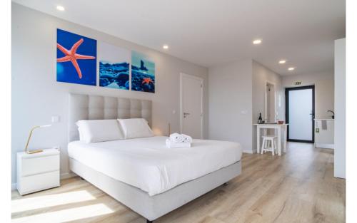 Dormitorio con cama blanca con estrella de mar en la pared en Estrella Beach APT Jardim do Mar, en Jardim do Mar
