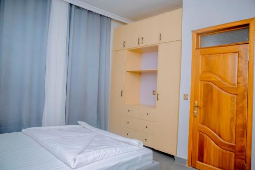 Mama's Favourite Apartments في كيغالي: غرفة نوم صغيرة بسرير وباب خشبي