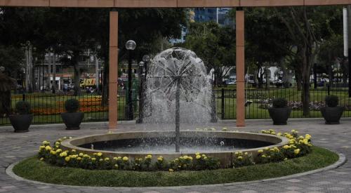 a fountain in a park with yellow flowers around it at Hab Pequeña baño compartido La Paz 4 in Lima