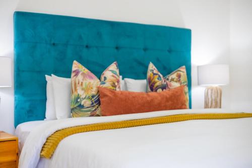a bed with a blue headboard and pillows at The Yellow Door Guesthouse in East London