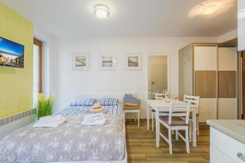 a bedroom with a bed and a table and a kitchen at BALTIC PARK A Apartamenty PIAMOLA in Stegna