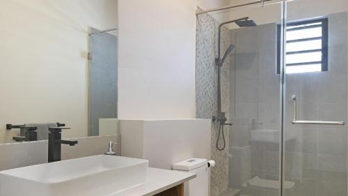 a white bathroom with a sink and a shower at One Bay Penthouse in Grand-Baie