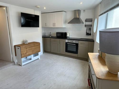 a kitchen with a stove and a microwave at Cozy 1 Bedroom Flat The Snug in Kent