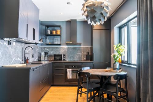 a kitchen with a table and chairs and a kitchen with gray cabinets at Skipperhuset 1, Bernt Berntsen suite in Tofta