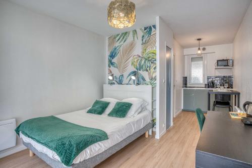 Cet appartement comprend une chambre avec un lit doté d'oreillers verts et une cuisine. dans l'établissement Élégant studio centre Marmande Mon Petit Appart, à Marmande
