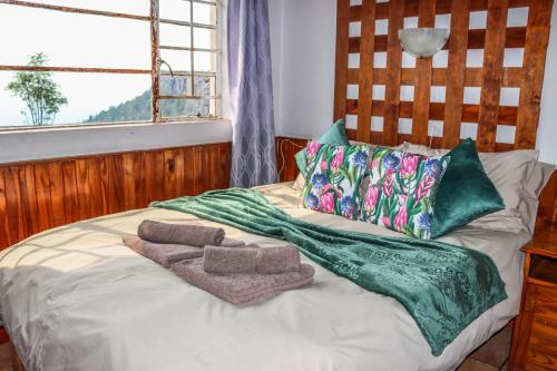 a bed with two towels on it with a window at Panorama Chalets & Rest Camp in Graskop