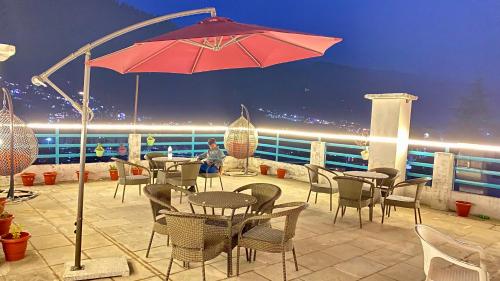 d'une terrasse avec des tables, des chaises et un parasol. dans l'établissement Hotel Mountain Meadows, à Manali