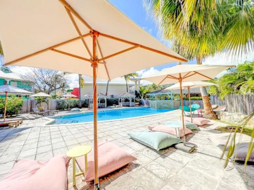 a pool with umbrellas and lounge chairs next to a swimming pool at Plage 37 Orient Bay beach front with pool access in Orient Bay