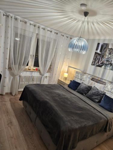 a bedroom with a large bed with curtains and a chandelier at schlafgut24 in Dortmund