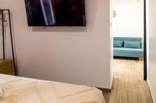 - une chambre avec un canapé et une télévision murale dans l'établissement Nîmes Centre - A 5 minutes des Arènes, à Nîmes