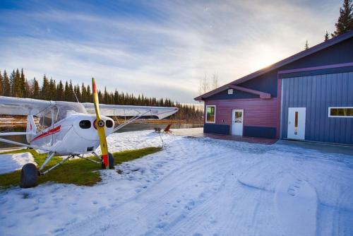 a small plane parked next to a building in the snow at Lakefront Aviators Aurora Retreat in North Pole
