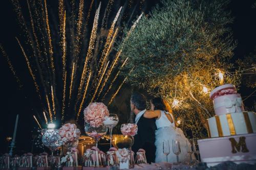 una sposa e uno sposo in piedi accanto a un tavolo con fuochi d'artificio di Hotel Imperiale a Terzigno