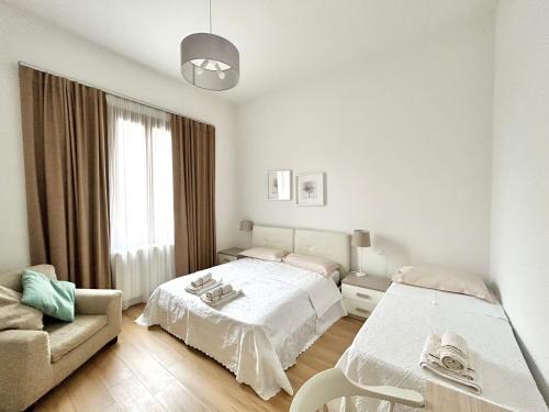 a white bedroom with a bed and a couch at Le Tre Orchidee Florence in Florence