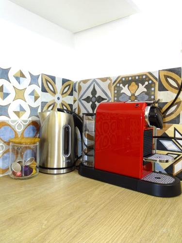 Un grille-pain rouge est installé au-dessus d'un comptoir de cuisine. dans l'établissement TILIA JOURDAN-Studio Cosy Aix Centre-Cours MIRABEAU-PARKING-WIFI-SMART TV-RUE CALME, à Aix-en-Provence