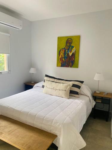 a bedroom with a white bed with a painting on the wall at Deptos Tuc in San Miguel de Tucumán