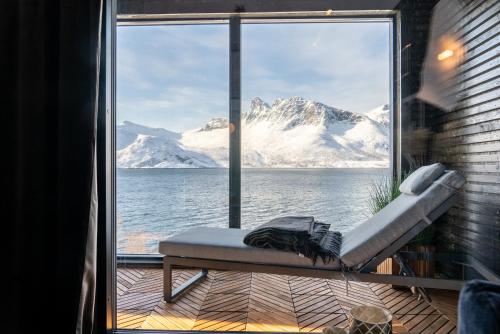 una ventana con vistas a las montañas cubiertas de nieve en Skipperhuset leilighet nr 2, en Tofta