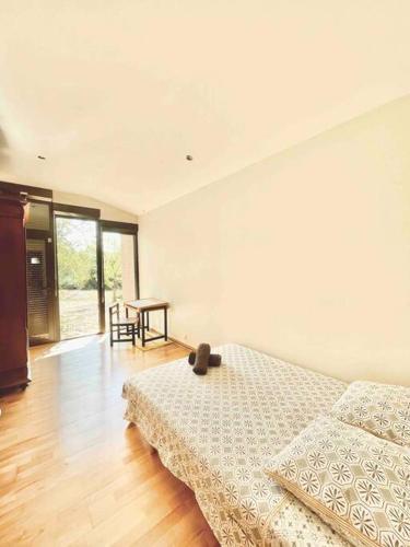 une chambre blanche avec un lit et une table dans l'établissement Maison d’archi 80’s avec piscine et toboggan, à Ventenac-Cabardès