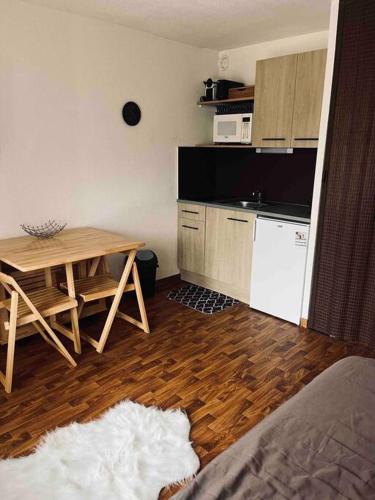 une cuisine avec une table et une petite cuisine avec une table et une cuisine dans l'établissement Studio confortable et chaleureux, vue magnifique, à Saint-Léger-les-Mélèzes