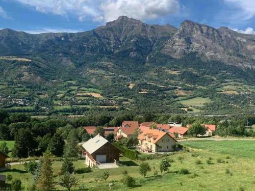 uma casa numa colina com montanhas ao fundo em Studio confortable et chaleureux, vue magnifique em Saint-Léger-les-Mélèzes