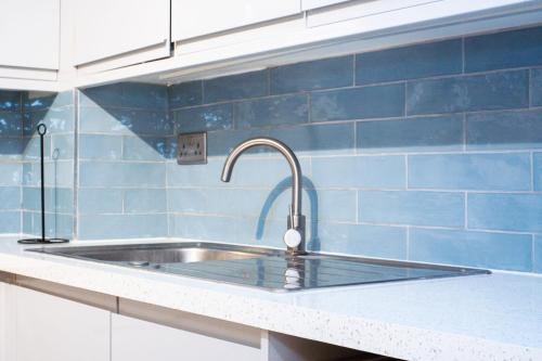 a stainless steel sink in a kitchen with blue tiles at The Perfect Spot in Alpha Grove in London