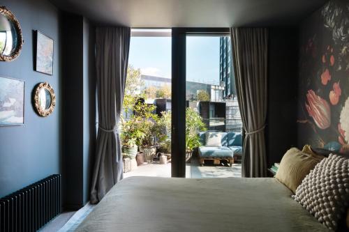 1 dormitorio con cama y ventana grande en Luxurious Penthouse, Expansive Wrap-Around Terrace en Londres