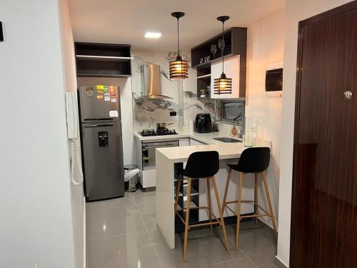 eine Küche mit einem Kühlschrank und einer Theke mit Barhockern in der Unterkunft El mirador paisa in Bello