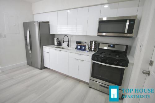 a kitchen with white cabinets and a stainless steel refrigerator at 251 Airport/Top House Apartments in Miami