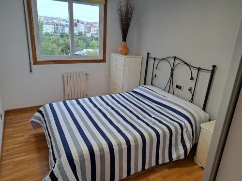 ein Schlafzimmer mit einem Bett mit einer gestreiften Decke in der Unterkunft Piso Millenium in Ourense