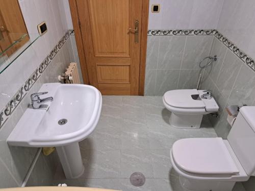 ein Badezimmer mit einem weißen Waschbecken und einem WC in der Unterkunft Piso Millenium in Ourense