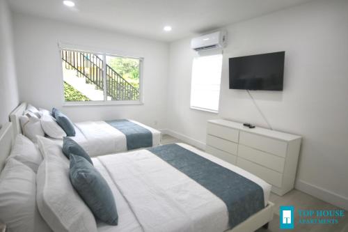 a bedroom with two beds and a flat screen tv at 251 Airport/Top House Apartments in Miami