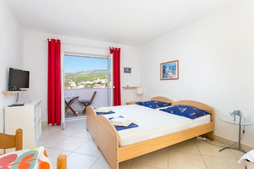 a bedroom with a bed and a large window at Family friendly apartments with a swimming pool Seget Vranjica, Trogir - 14409 in Donji Seget