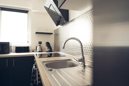 une cuisine avec un évier et une fenêtre dans l'établissement Mon nid d'amour!, à Dunkerque