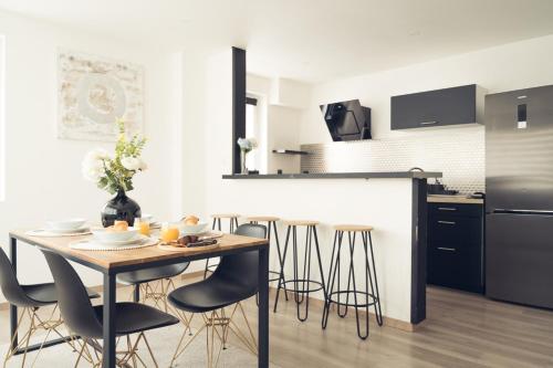 - une cuisine et une salle à manger avec une table et des tabourets dans l'établissement Mon nid d'amour!, à Dunkerque