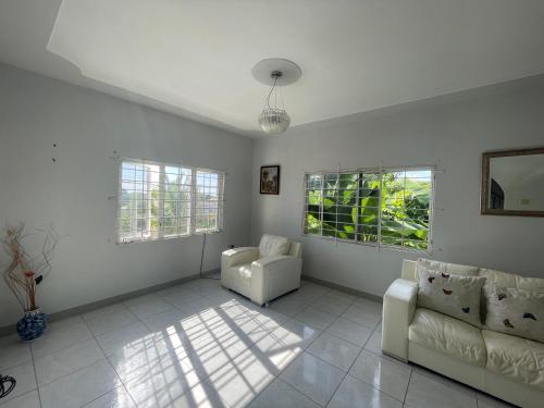 a living room with two chairs and a couch and windows at The Retreat in Lyssons