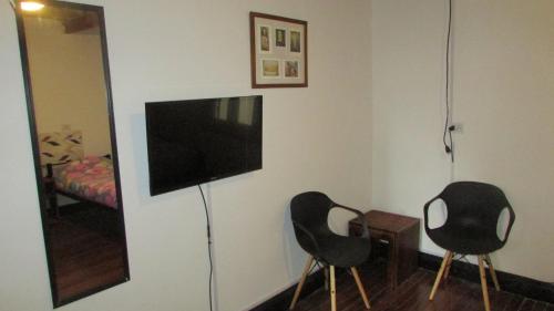 due sedie nere in una stanza con una televisione di IDEAL CENTER a Buenos Aires