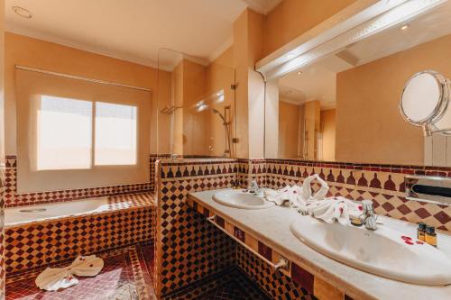 La salle de bains est pourvue de 2 lavabos, d'un miroir et d'une baignoire. dans l'établissement Palace Jena, à Marrakech