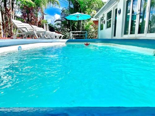 a swimming pool with blue water and an umbrella at 5BD House - Pool+BBQ+King beds - 3 min to beach in Hollywood