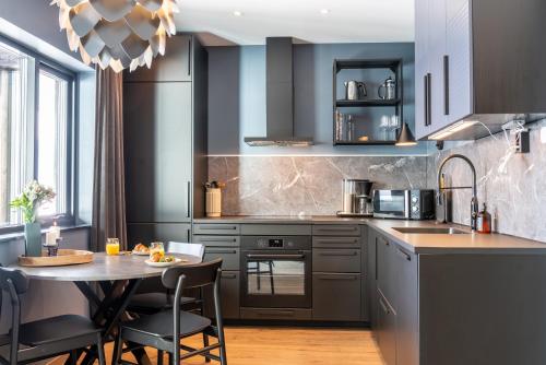 a kitchen with black cabinets and a table with chairs at Skipperhuset leilighet nr 4 in Tofta