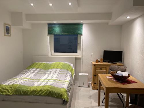 Schlafzimmer mit einem Bett, einem Tisch und einem TV in der Unterkunft Apartment Geigelsteinstrasse in Schleching