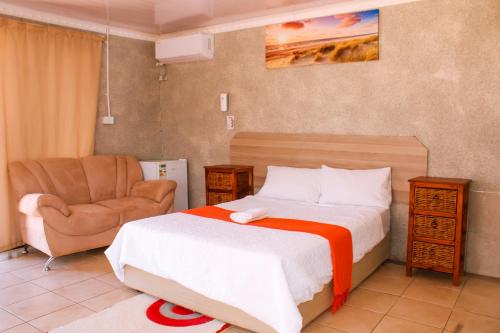 um quarto com uma cama, uma cadeira e um sofá em Godmill City Guesthouse Taung em Lethola