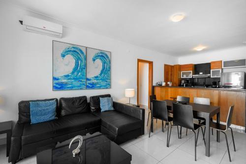 a living room with a black couch and a table and chairs at Escape Apartments, Balcony, Pool, Gym & Spa in La Julia in Santo Domingo