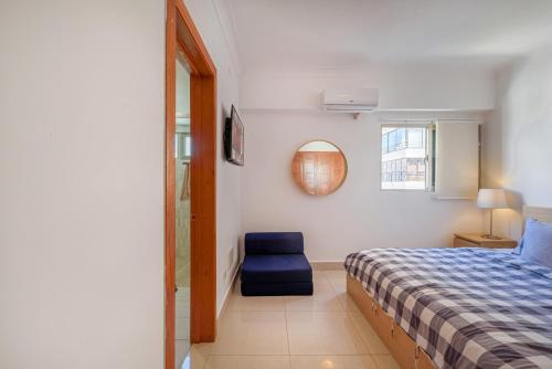 a bedroom with a bed and a blue chair at Escape Apartments, Balcony, Pool, Gym & Spa in La Julia in Santo Domingo
