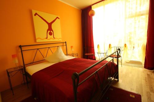 a bedroom with a bed with red sheets and a window at Arthotel Landhaus Zur Alten Gärtnerei in Zossen