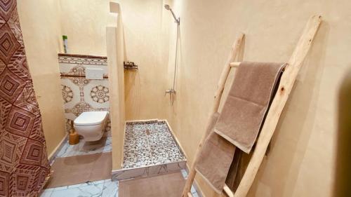 La salle de bains est pourvue de toilettes, d'une douche et d'une serviette. dans l'établissement SOUS LE SOLEIL Chez Jérôme et Pamela chambre Marrakchi, à Marrakech