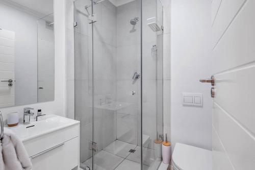 a white bathroom with a shower and a sink at Rooftop with breathtaking views of Table Mountain. in Cape Town