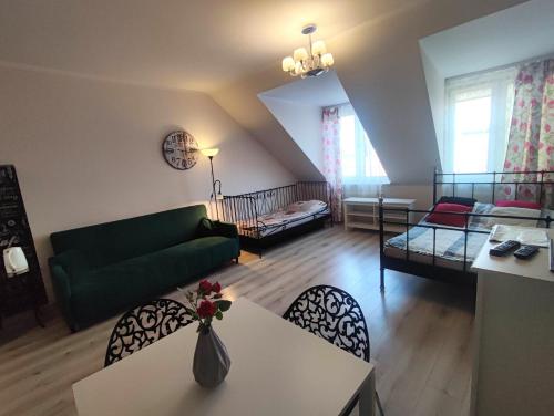 シュチェチンにあるKGHN Apartments Wyszyńskiego 12 Brama Portowaのリビングルーム(緑のソファ、テーブル、椅子付)