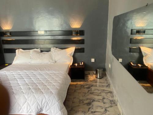 a bedroom with a bed with white sheets and pillows at Sunrise Center Bonapriso - 102 in Douala